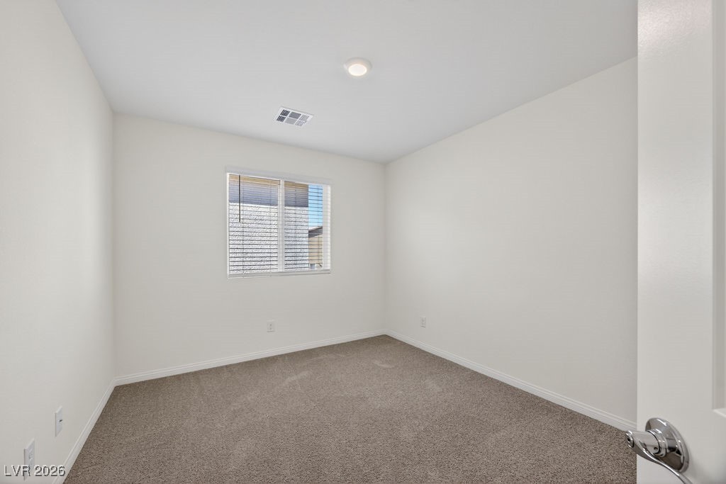 Empty carpeted room with a window and horizontal blinds, viewed from the doorway.