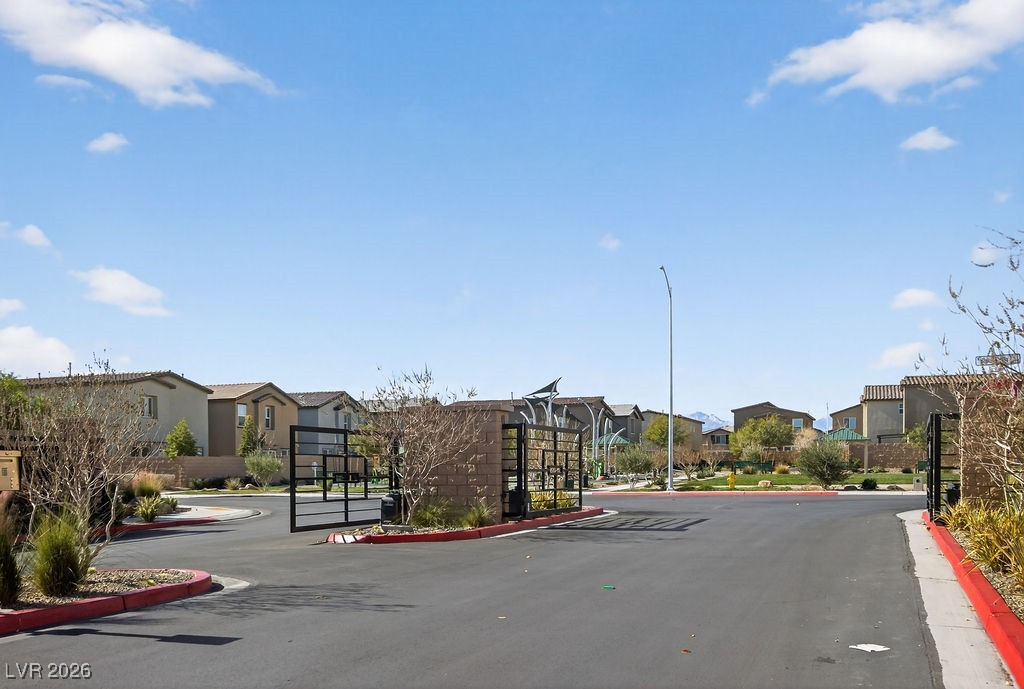 Gated residential community entrance with desert landscaping and homes beyond.