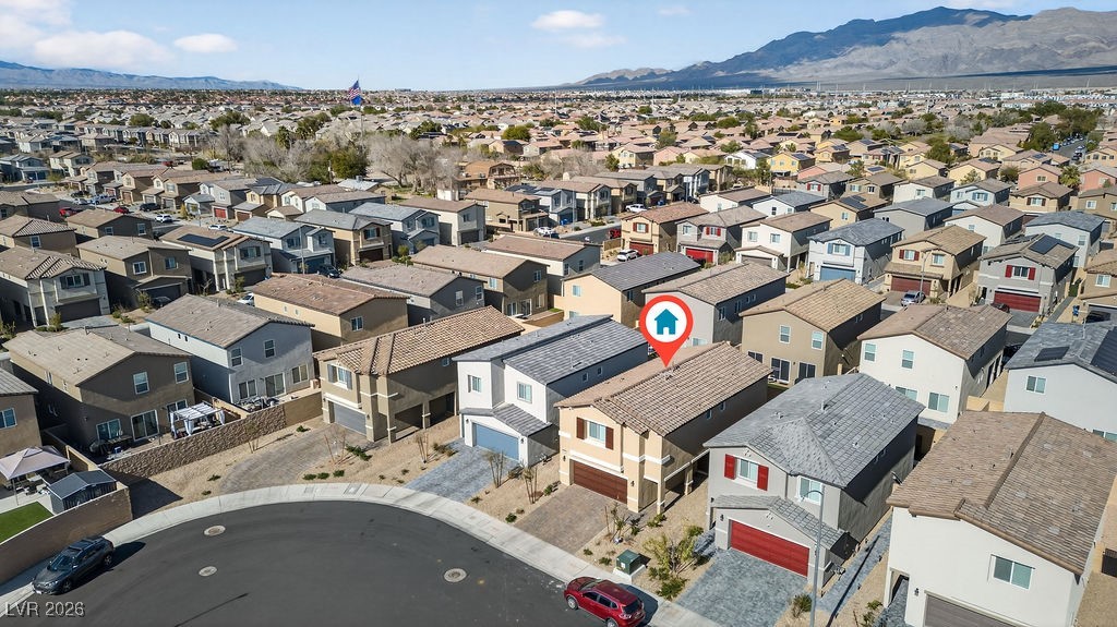 Aerial view of a suburban home among North Las Vegas rooftops, with mountains in the distance.