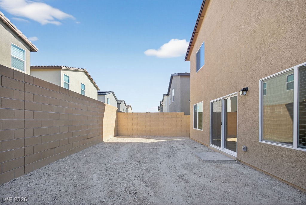 Enclosed dirt backyard with block walls and sliding glass doors.