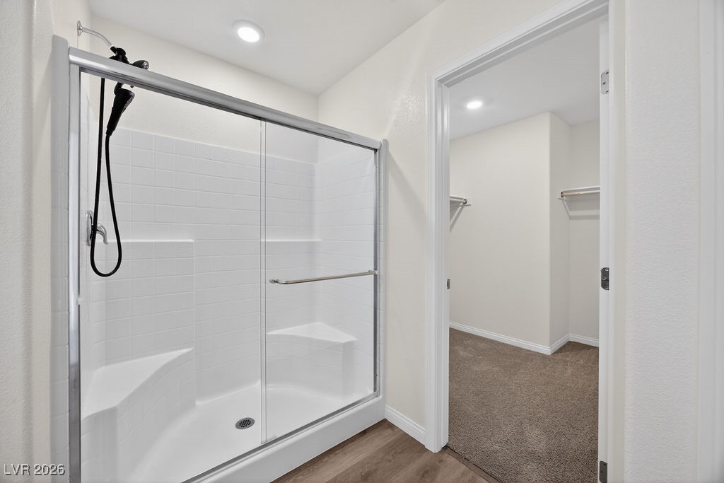 Bathroom with a glass-enclosed tiled shower and built-in seats beside an open walk-in closet.
