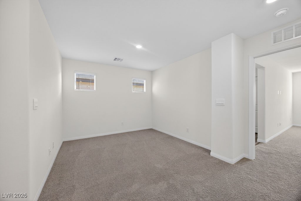 Empty carpeted room with two small windows and an open doorway.