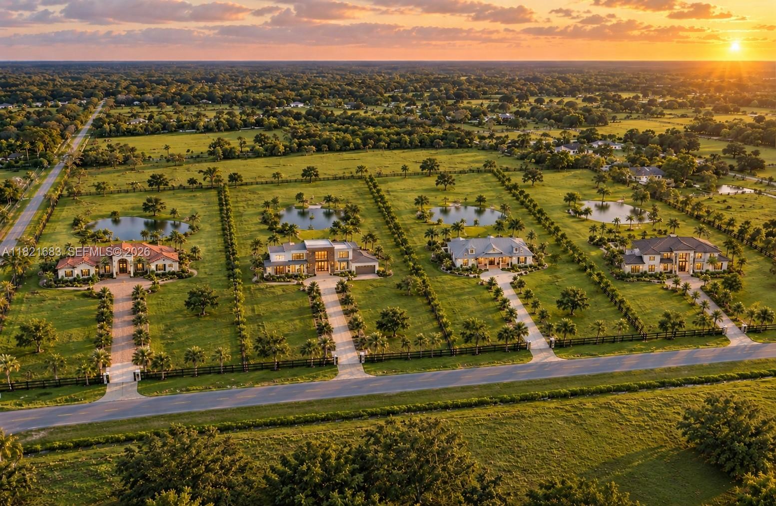 Aerial view of homes on spacious landscaped lots with ponds at sunset.