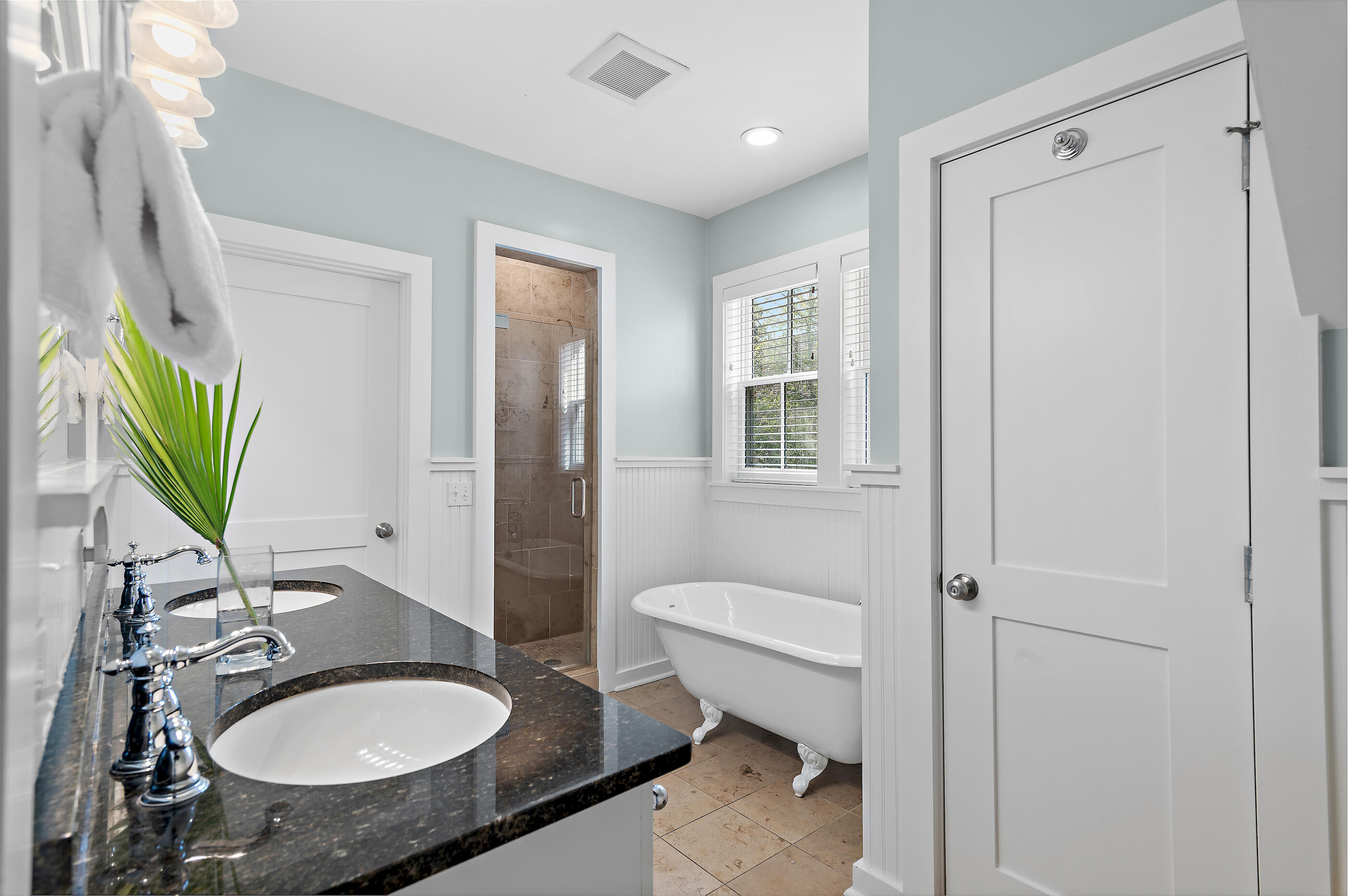 Bathroom with a dark double-sink vanity, clawfoot tub, and tiled walk-in shower.
