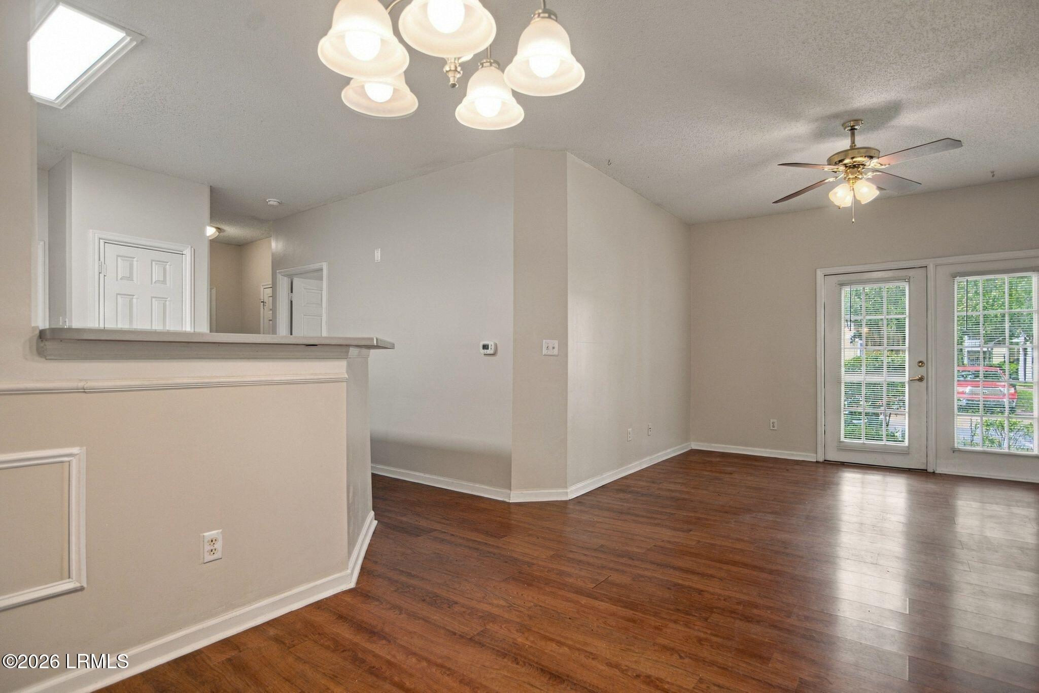 Vacant living and dining area with dark hardwood floors and glazed double doors.