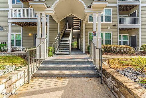 Residential building entrance with a central staircase, arched portico, and stone planters.