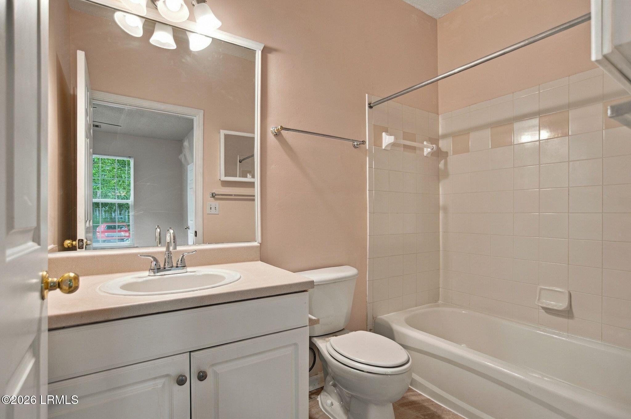 Bathroom with a white vanity, toilet, and bathtub with tiled shower surround.