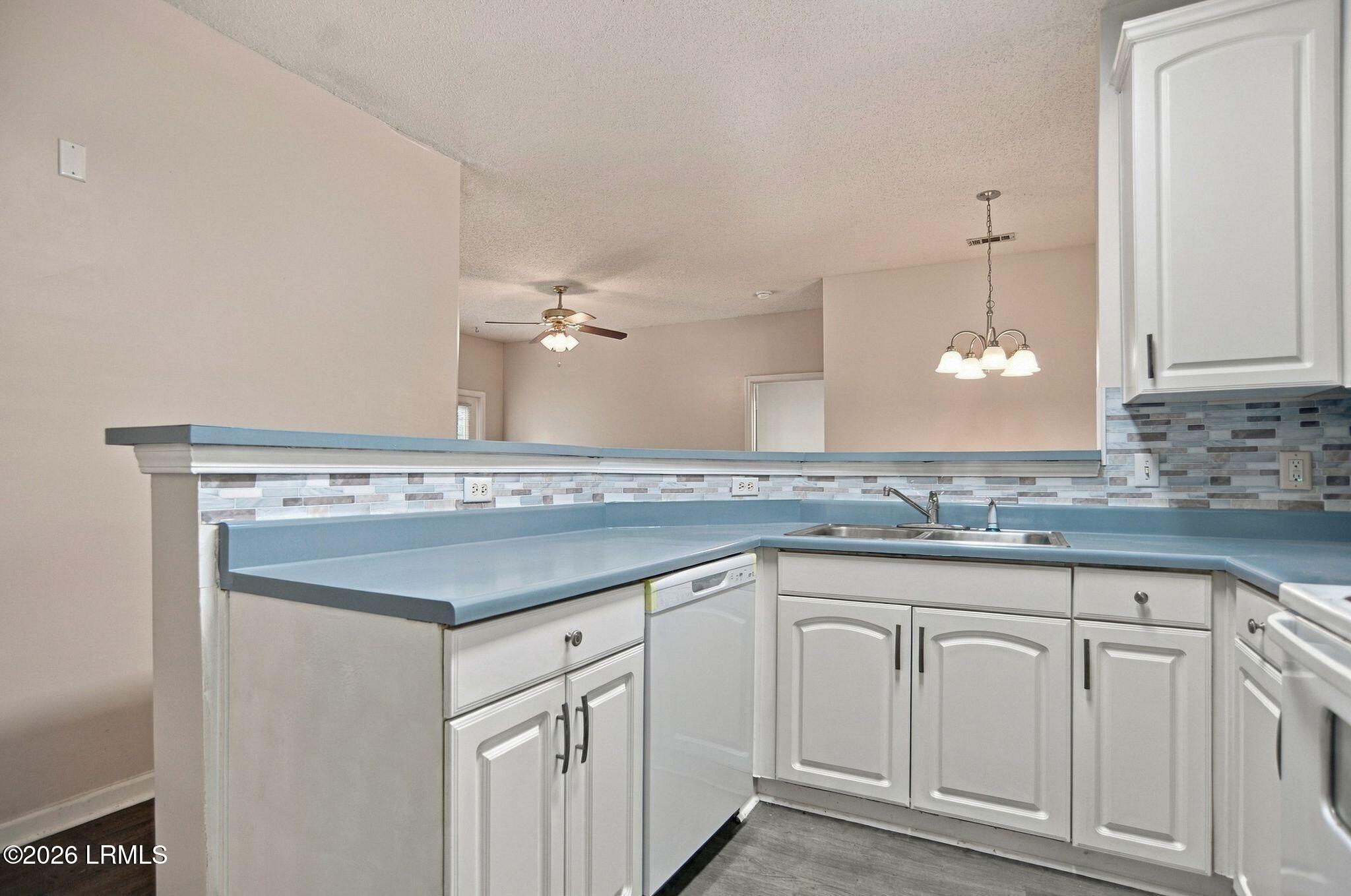 Kitchen with blue countertops, white cabinets, and a gray-and-blue mosaic backsplash.