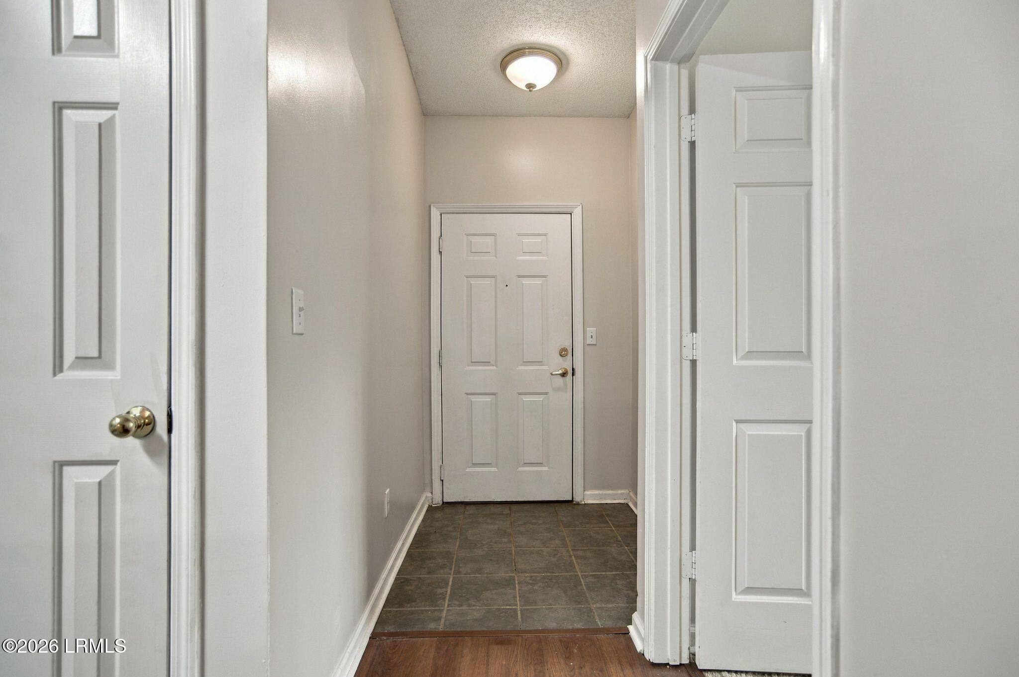 Entry hall with dark tile flooring, a six-panel front door, and open interior doors.