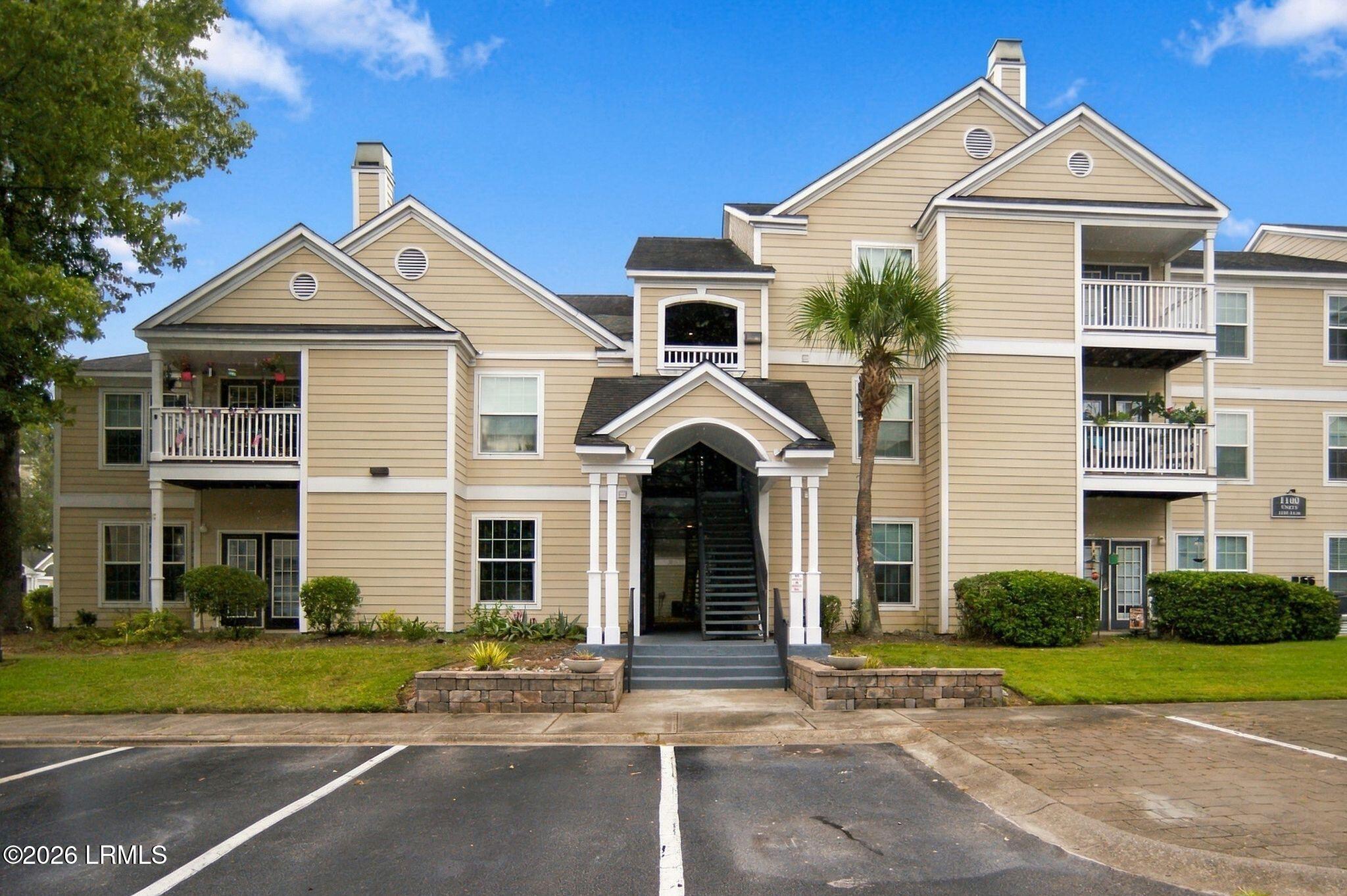Beige multi-unit building with balconies and a central stairway entrance.