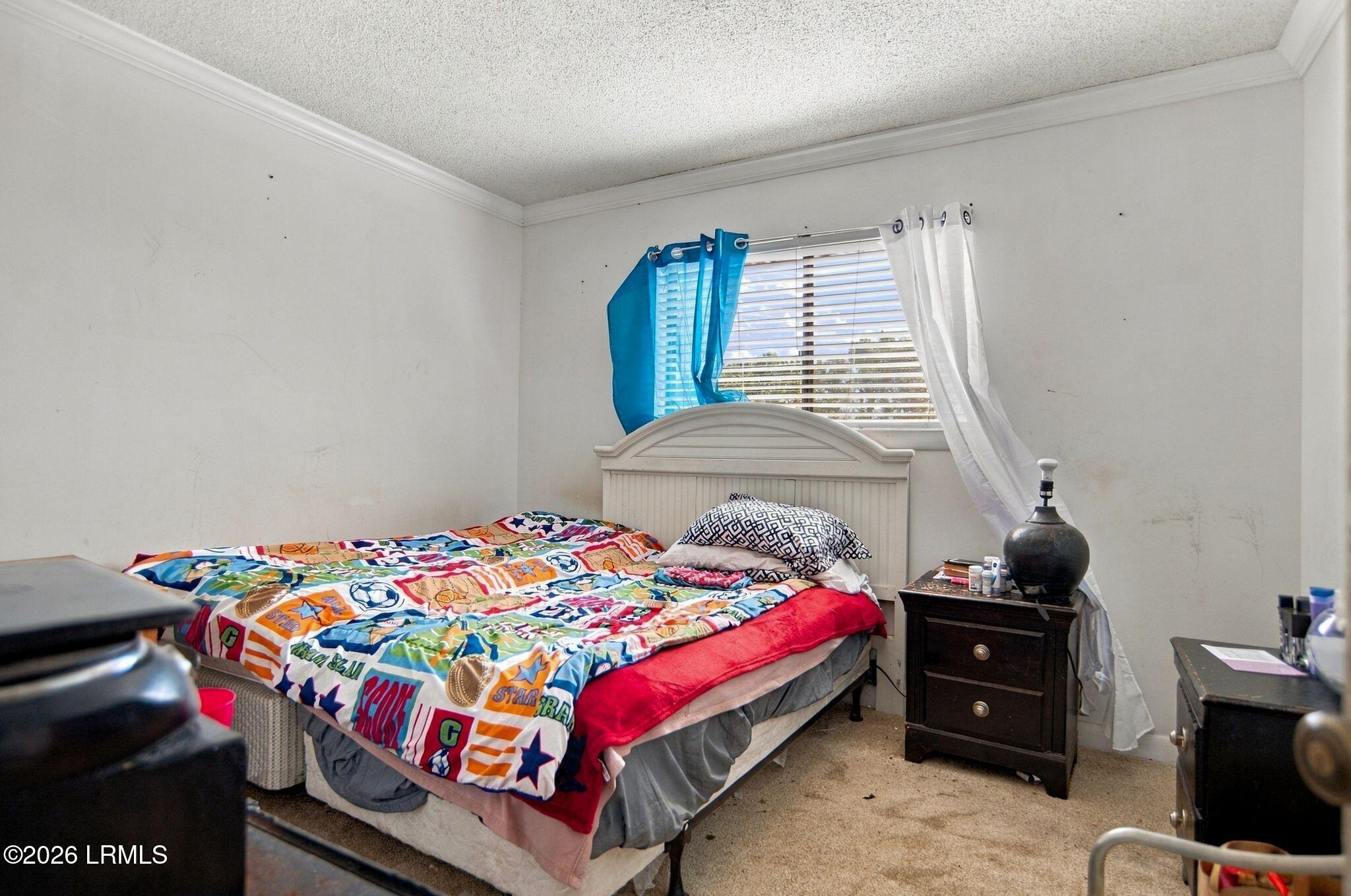 Bedroom with colorful sports-themed bedding, a white headboard, and blue and white curtains.