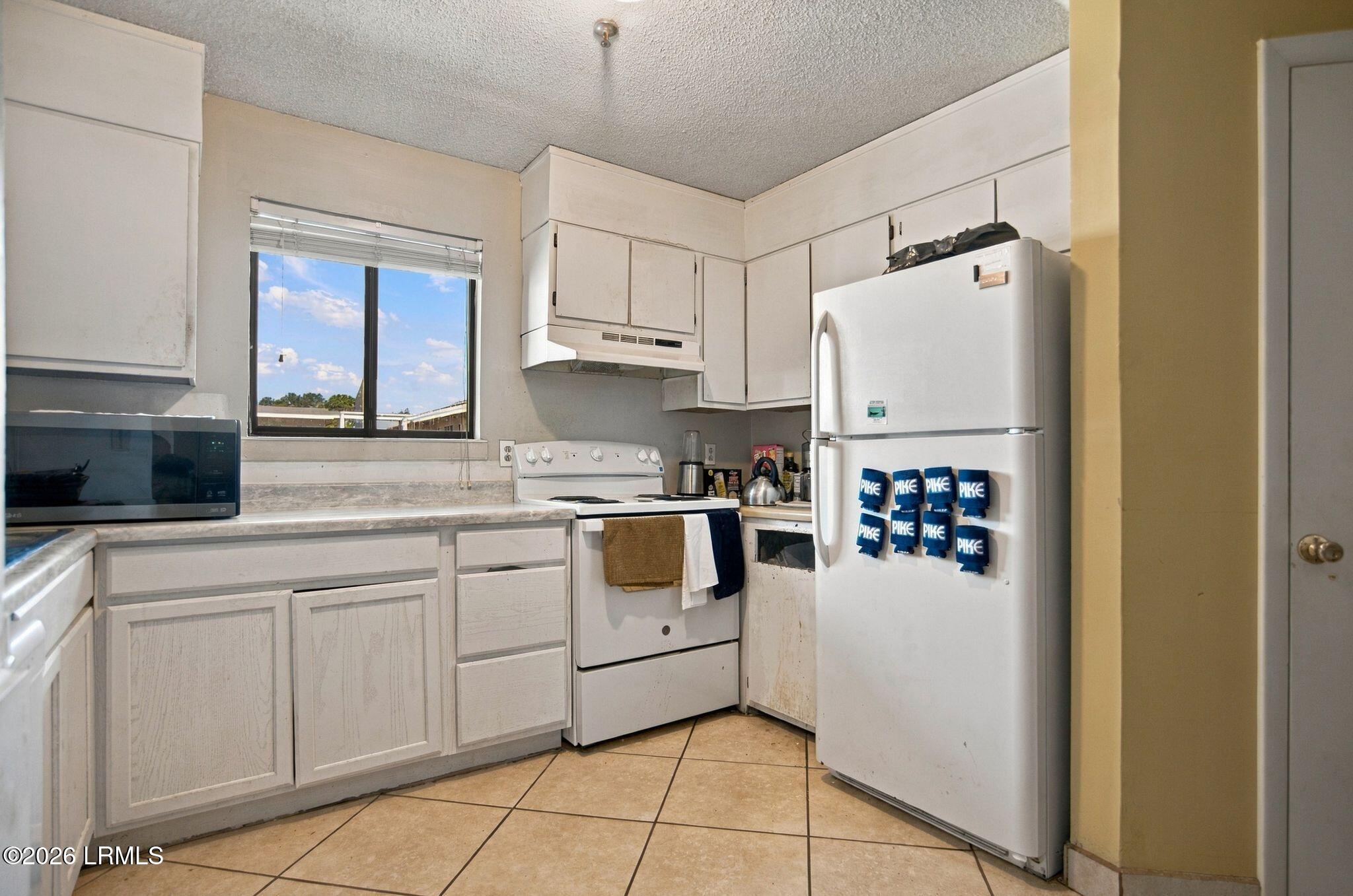 Kitchen with white cabinets, a freestanding range, and a refrigerator covered with blue Pike magnets.
