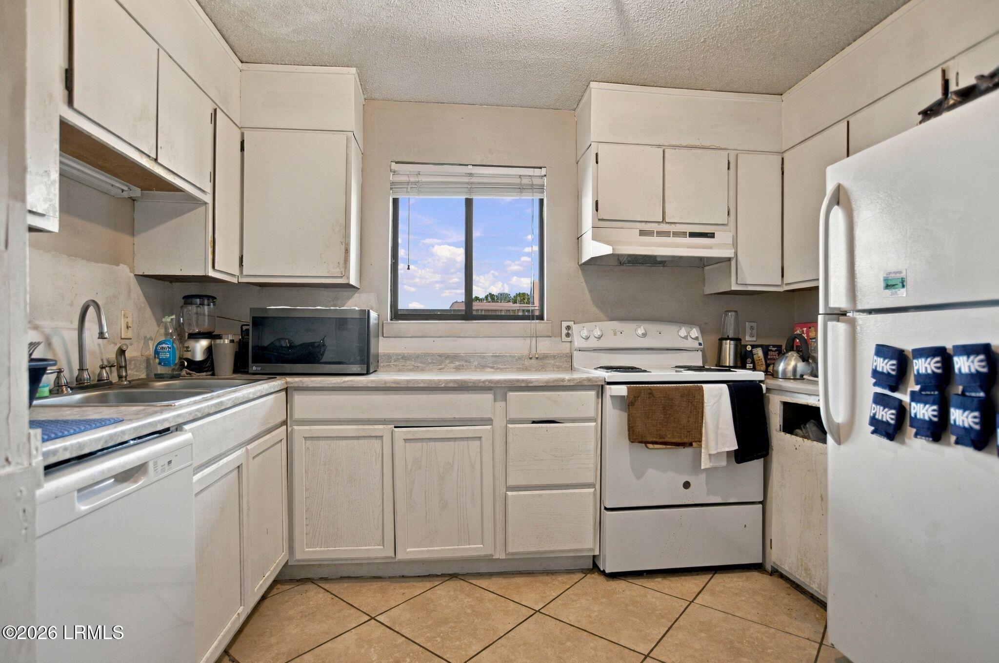 Kitchen with white cabinets, tiled counters, an electric range, and a window above the counter.