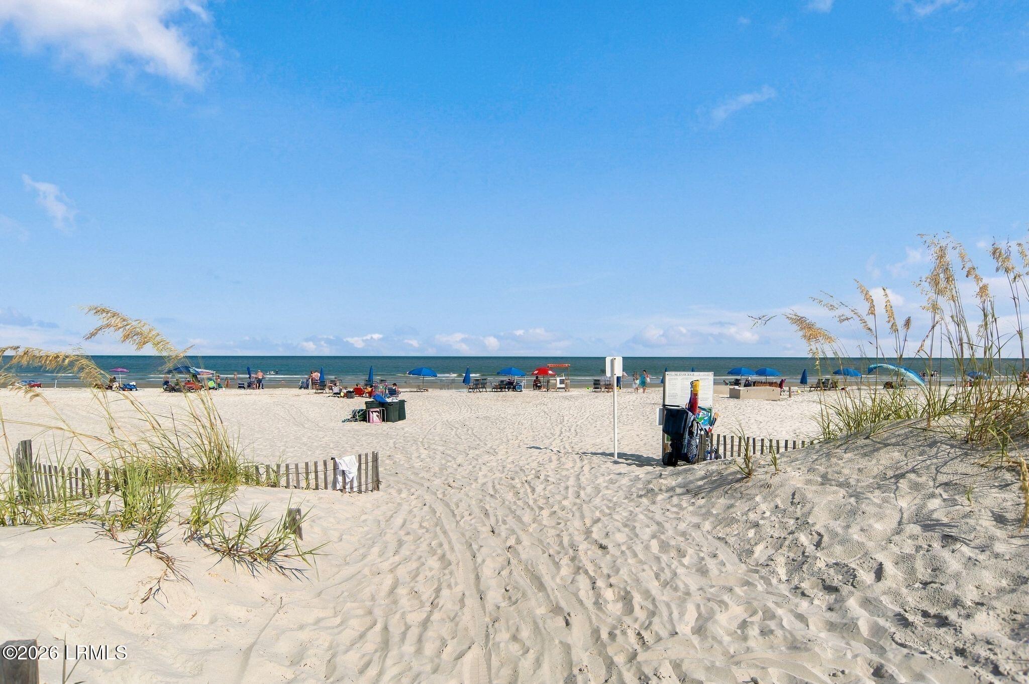 Hilton Head beach with ocean views, sandy dunes, beach grass, and colorful umbrellas.