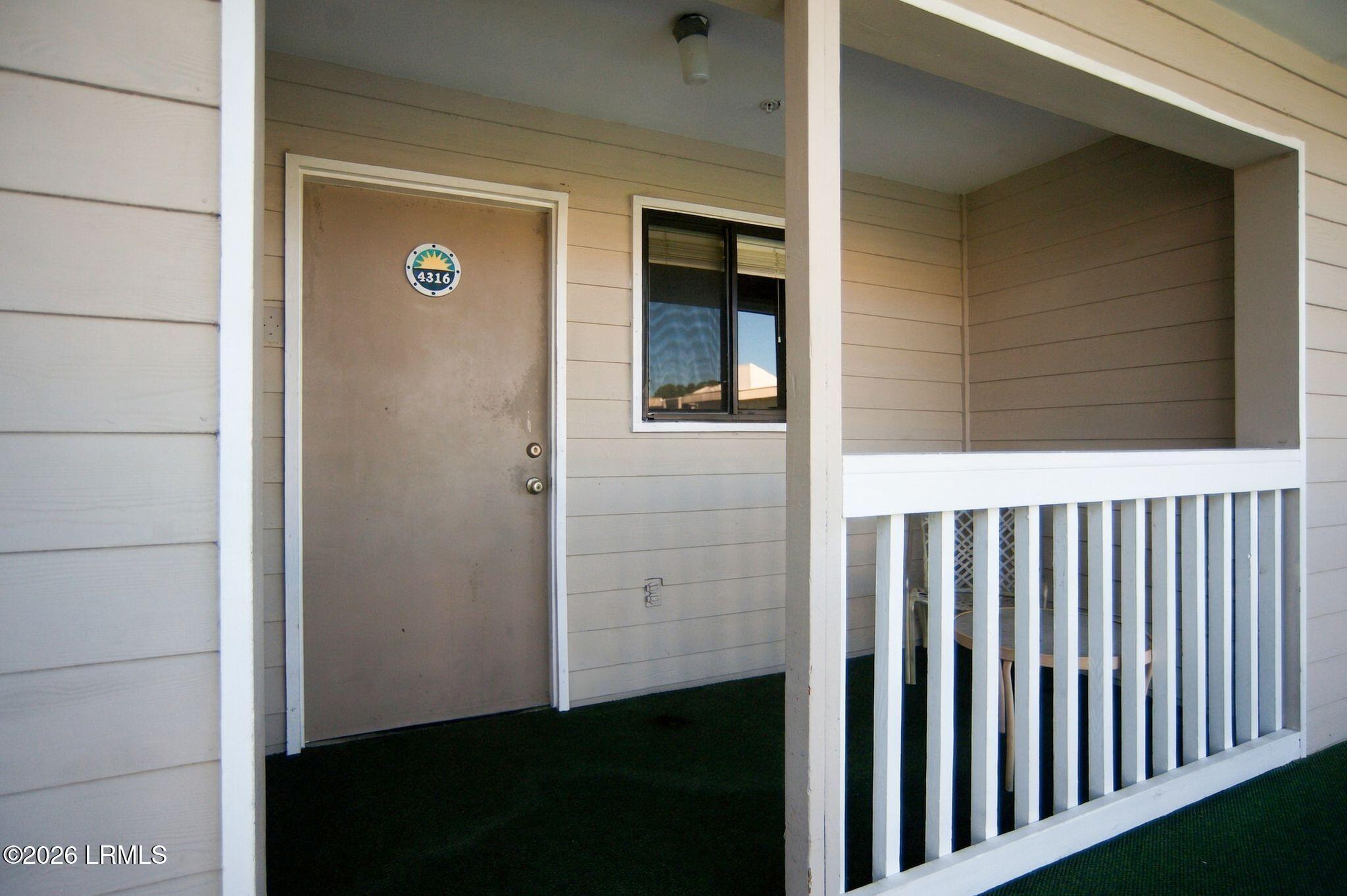 Unit 4316 entrance with a taupe door and covered porch with white railing.