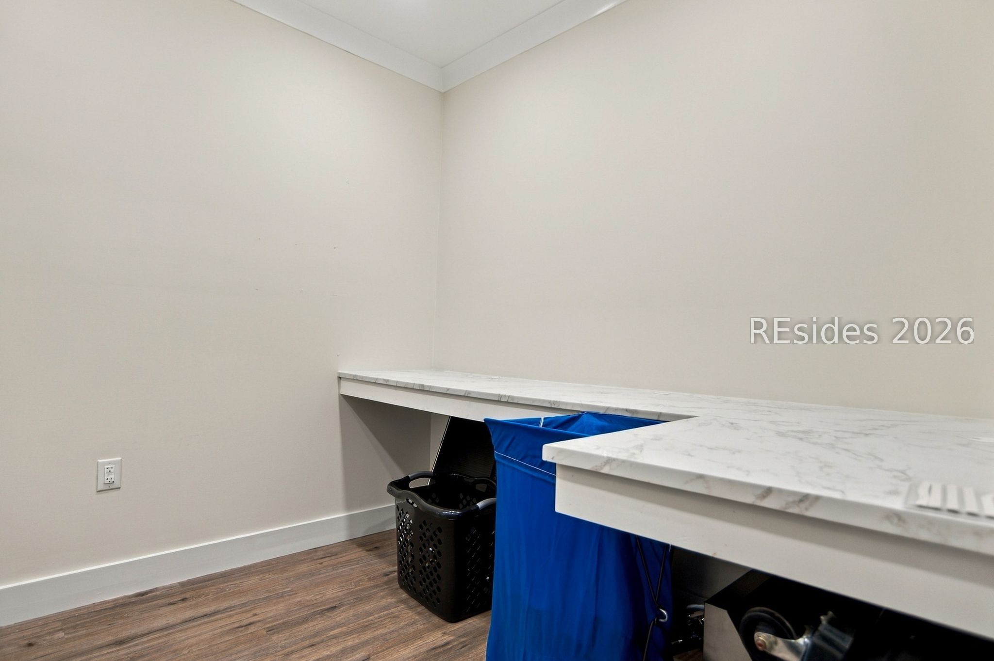 Interior room with an L-shaped marble-look counter and laundry baskets stored underneath.