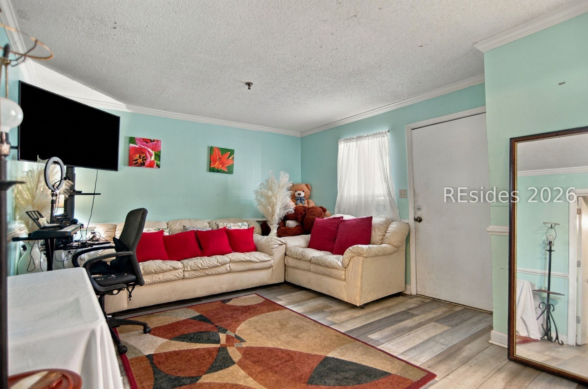Living room with cream sofas, red cushions, aqua walls, and a geometric rug.