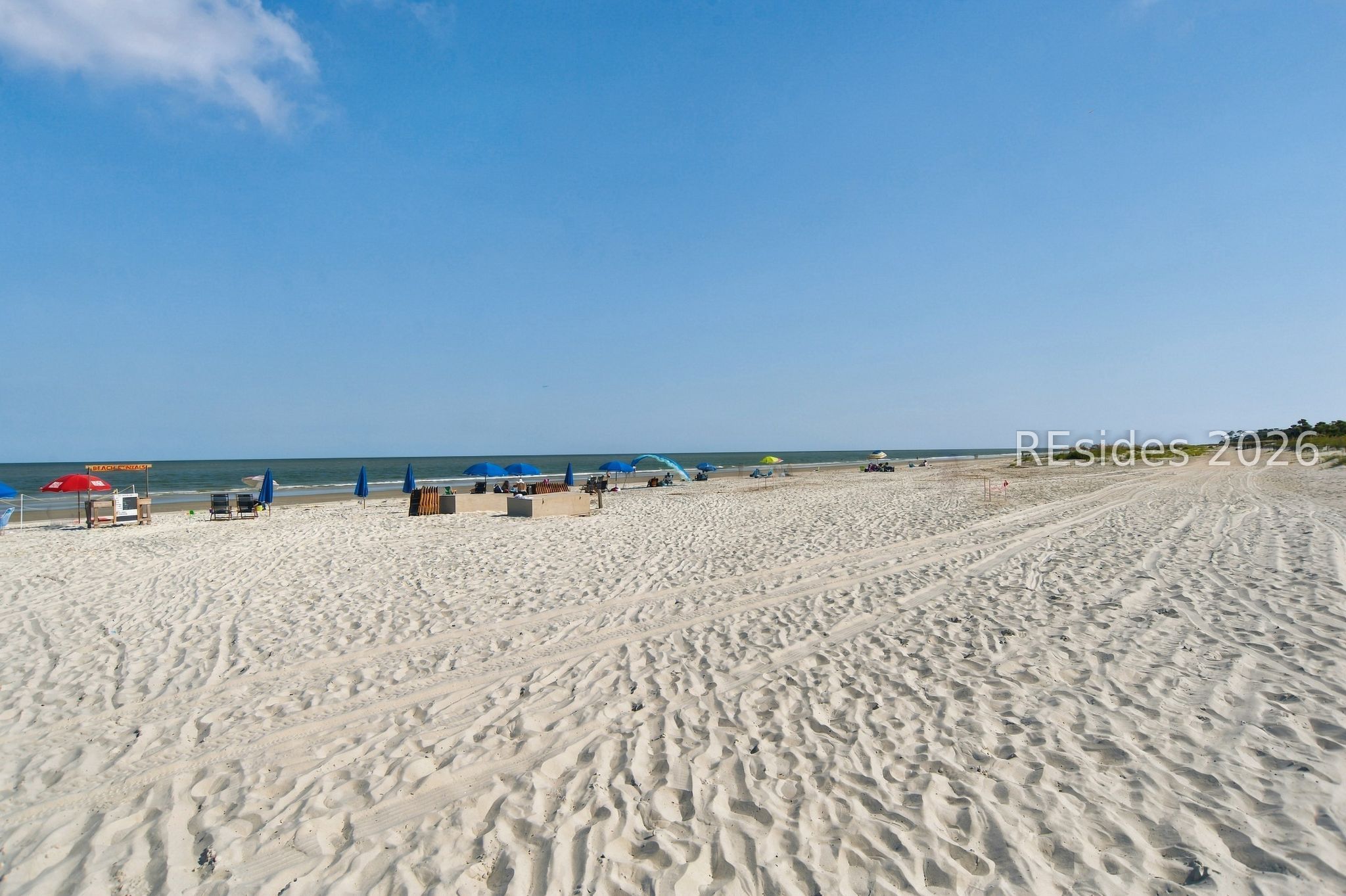 Sandy Hilton Head beach with colorful umbrellas, beach chairs, and ocean views.