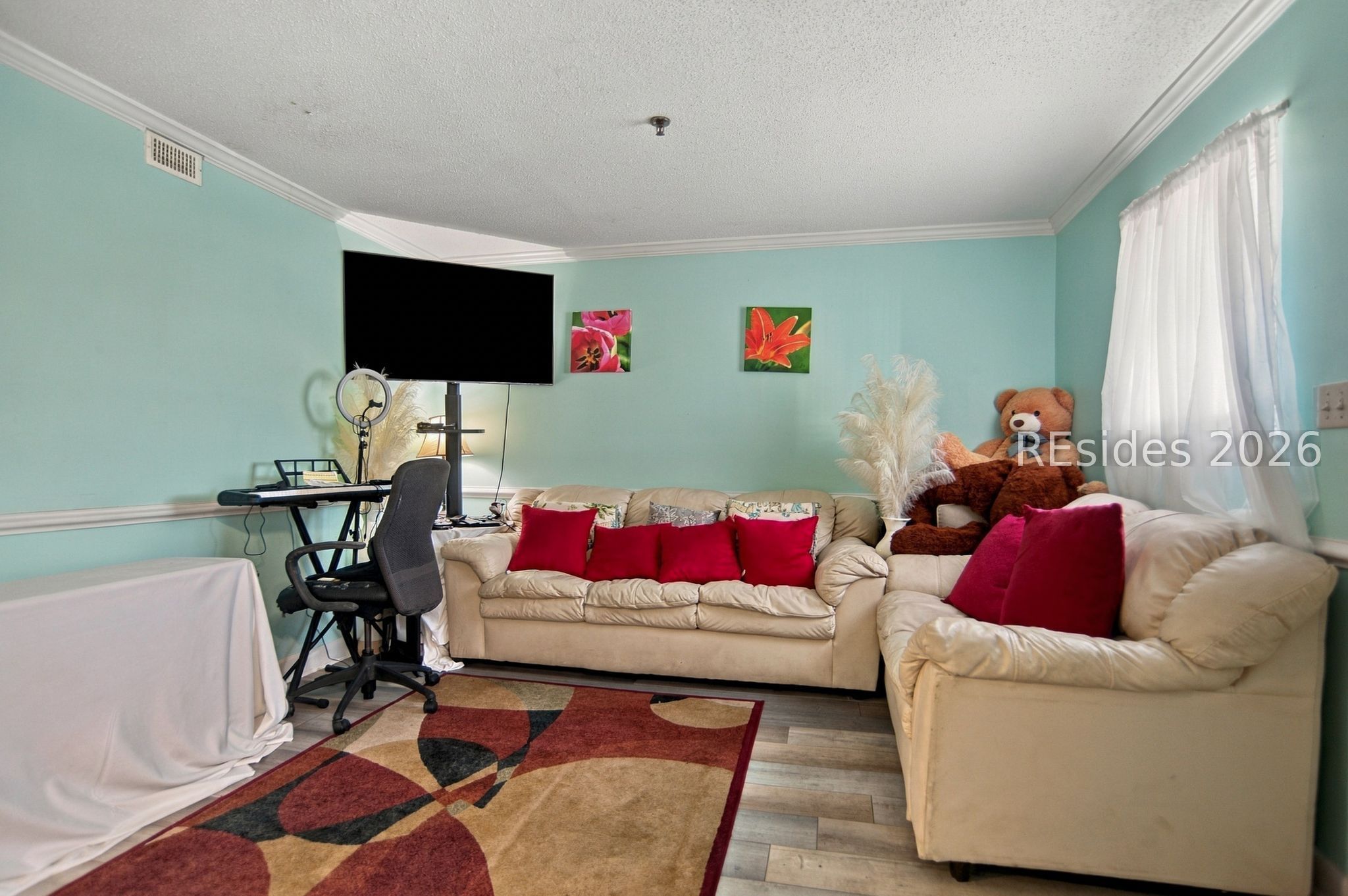 Living room with cream leather sofas, red cushions, mint-green walls, and a keyboard workstation.
