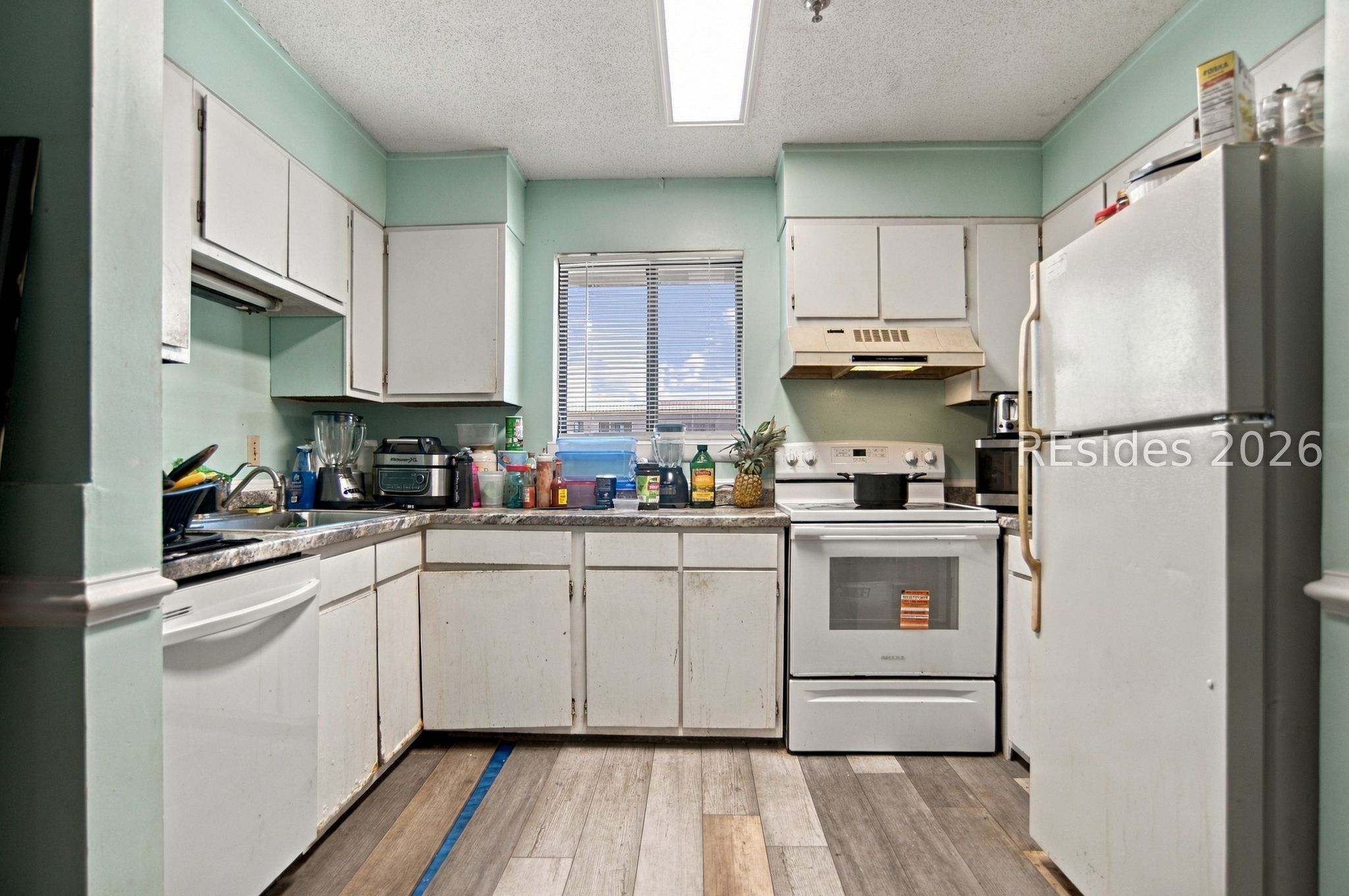 Kitchen with mint-green walls, white cabinets, and a full-size refrigerator beside the stove.