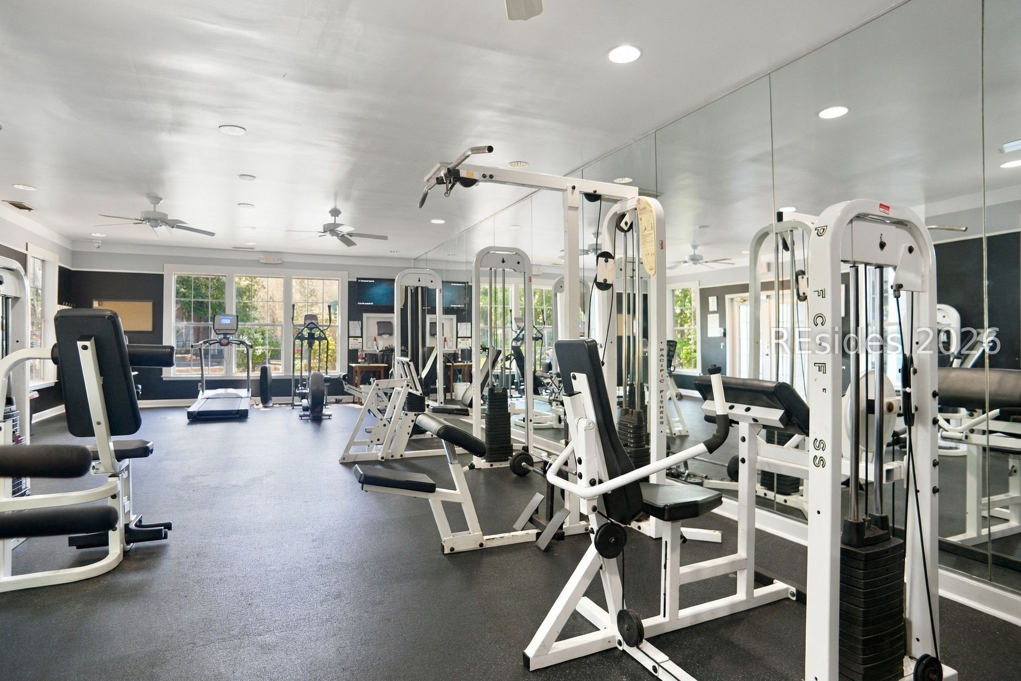 Fitness center with weight machines, mirrored walls, and large windows.
