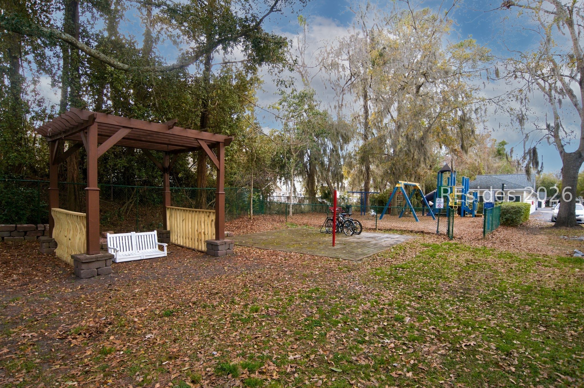 Community playground with swings, climbing equipment, and a wooden pergola