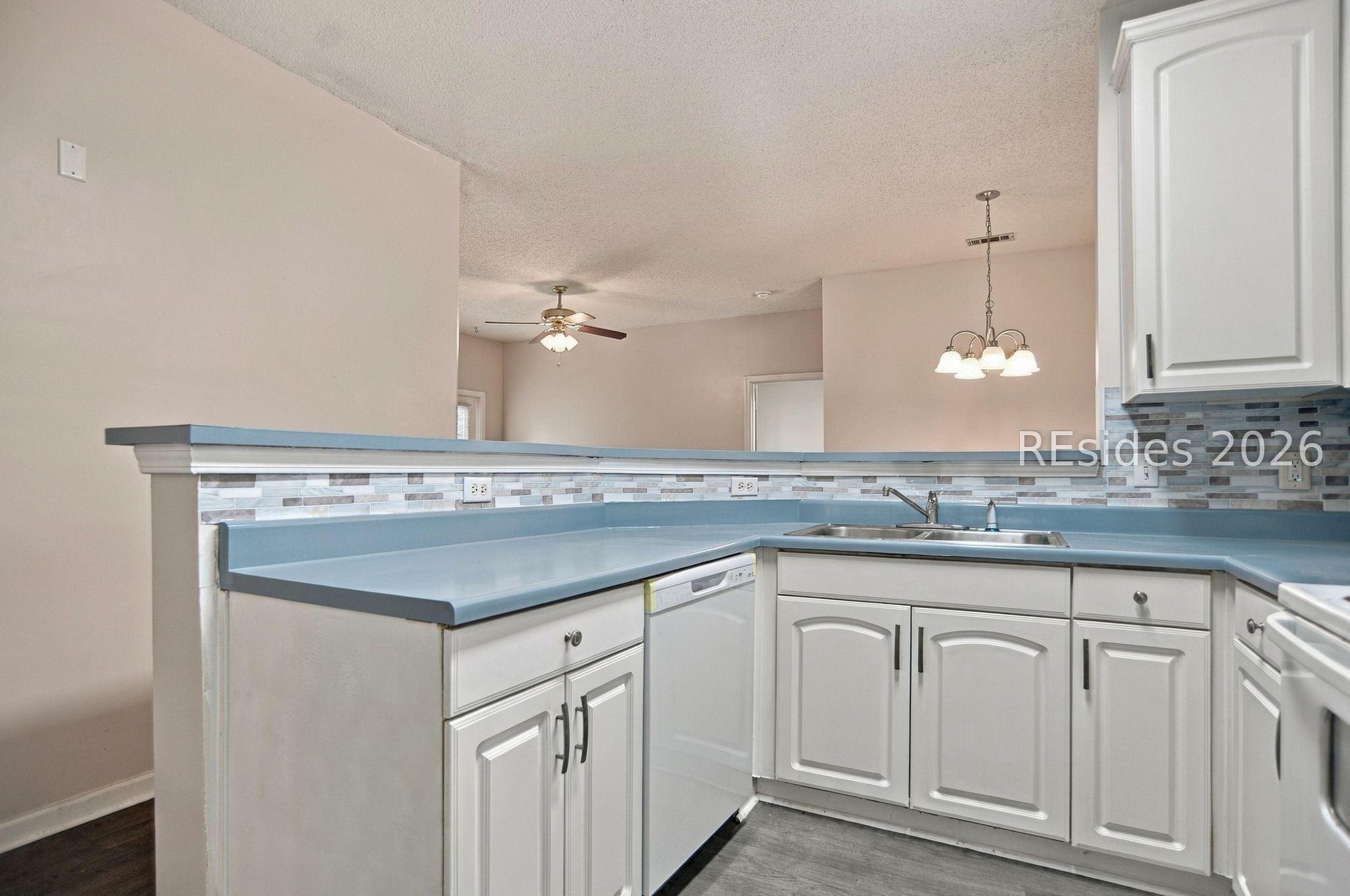 Kitchen with blue countertops, white cabinets, and a multicolored tile backsplash.