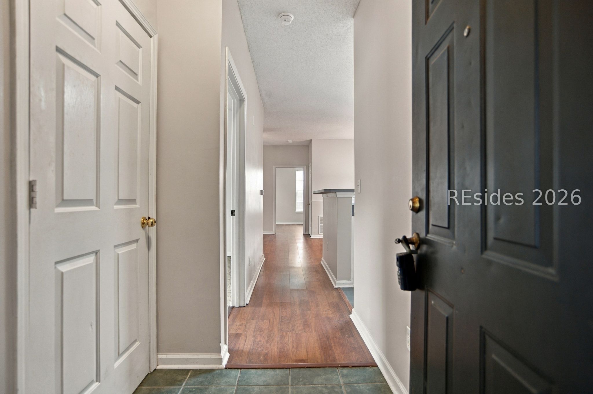 Apartment entry hall with wood flooring, white doors, and a glimpse of the kitchen.