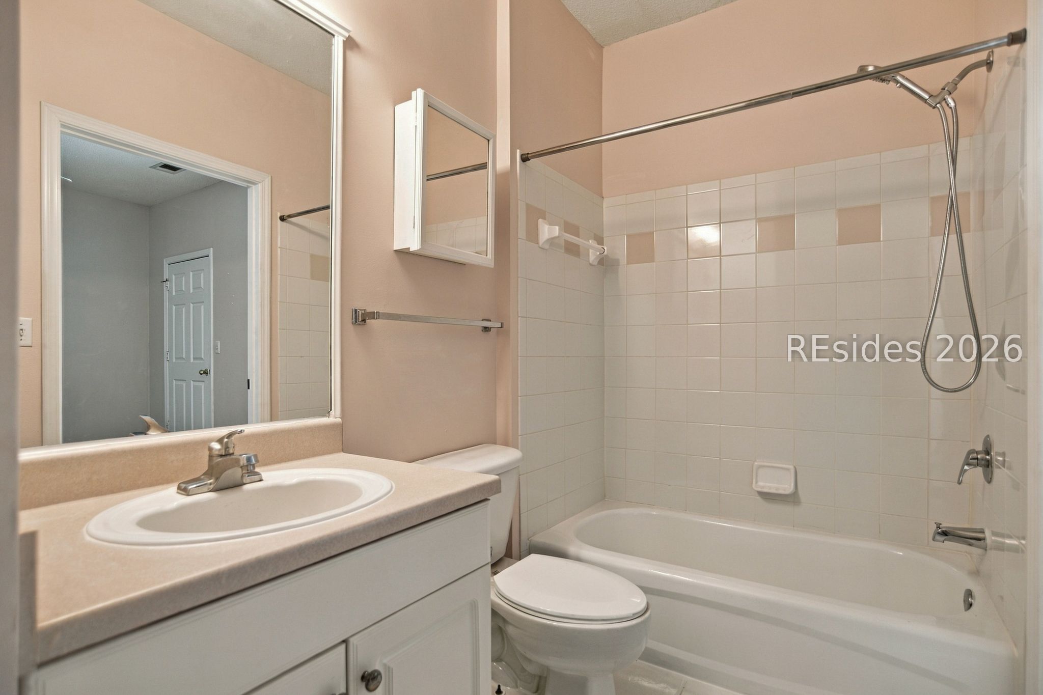 Bathroom with a white vanity, toilet, and bathtub with tiled shower surround.