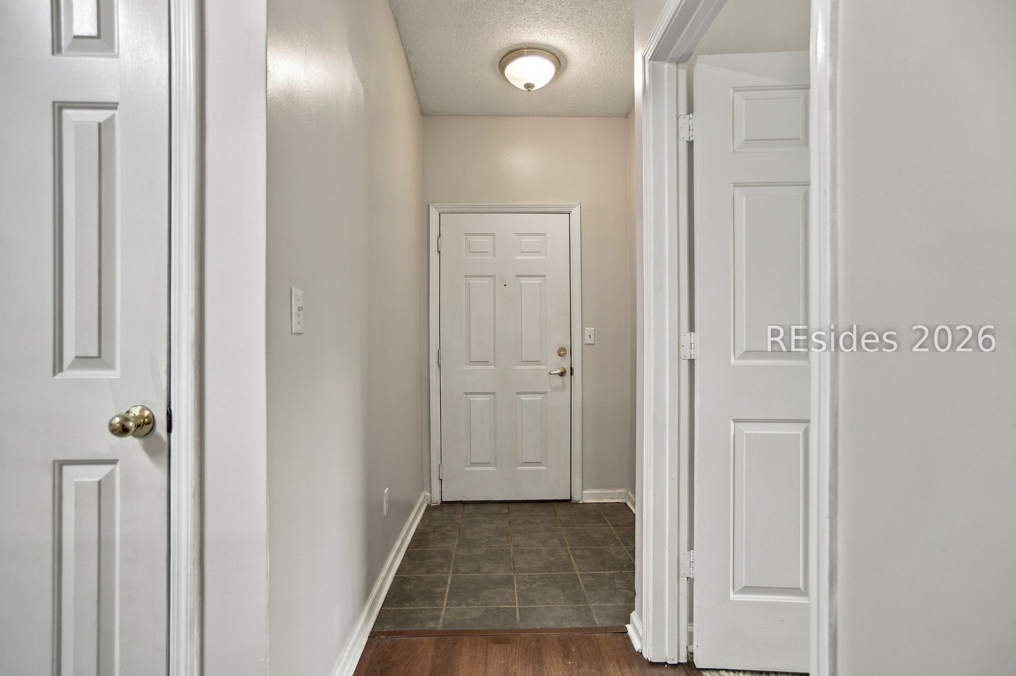 Apartment entry hall with a white paneled front door and gray tile flooring.