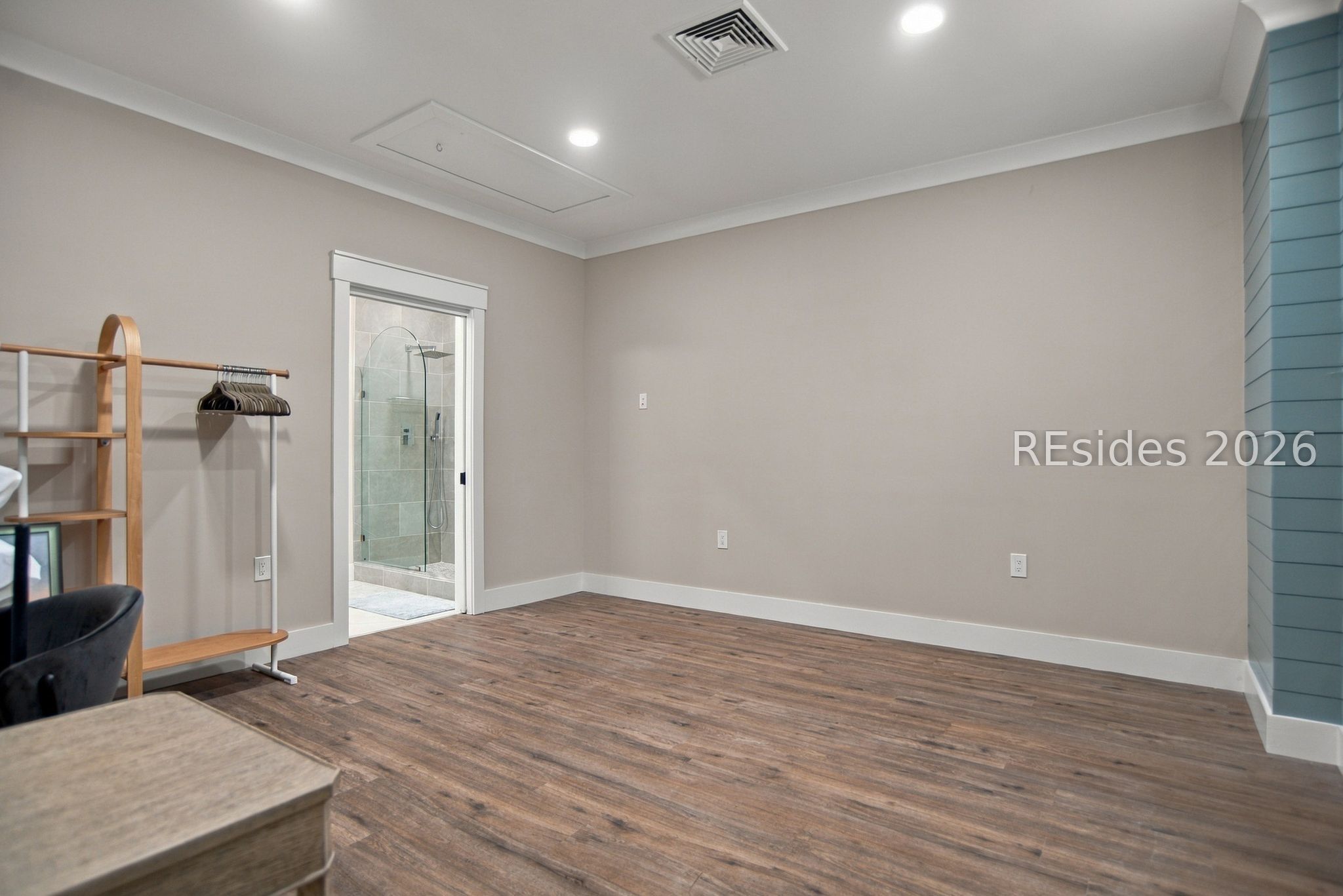 Interior room with wood-look flooring, a clothing rack, and a glass shower doorway.