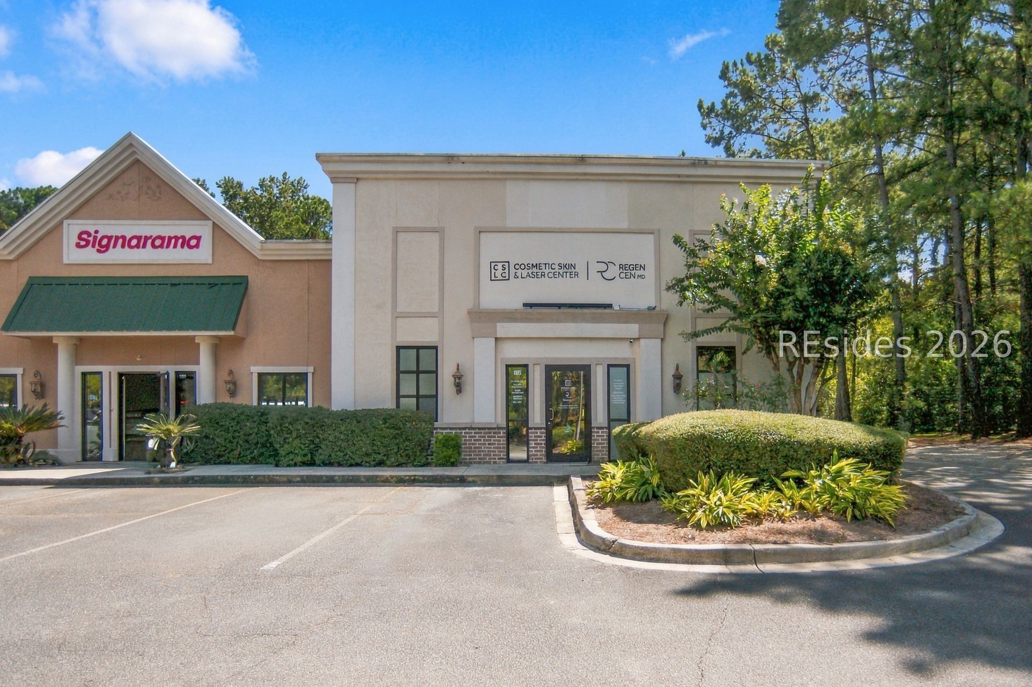 Commercial building with Signarama and cosmetic skin and laser center storefronts, landscaped shrubs, and a parking area.