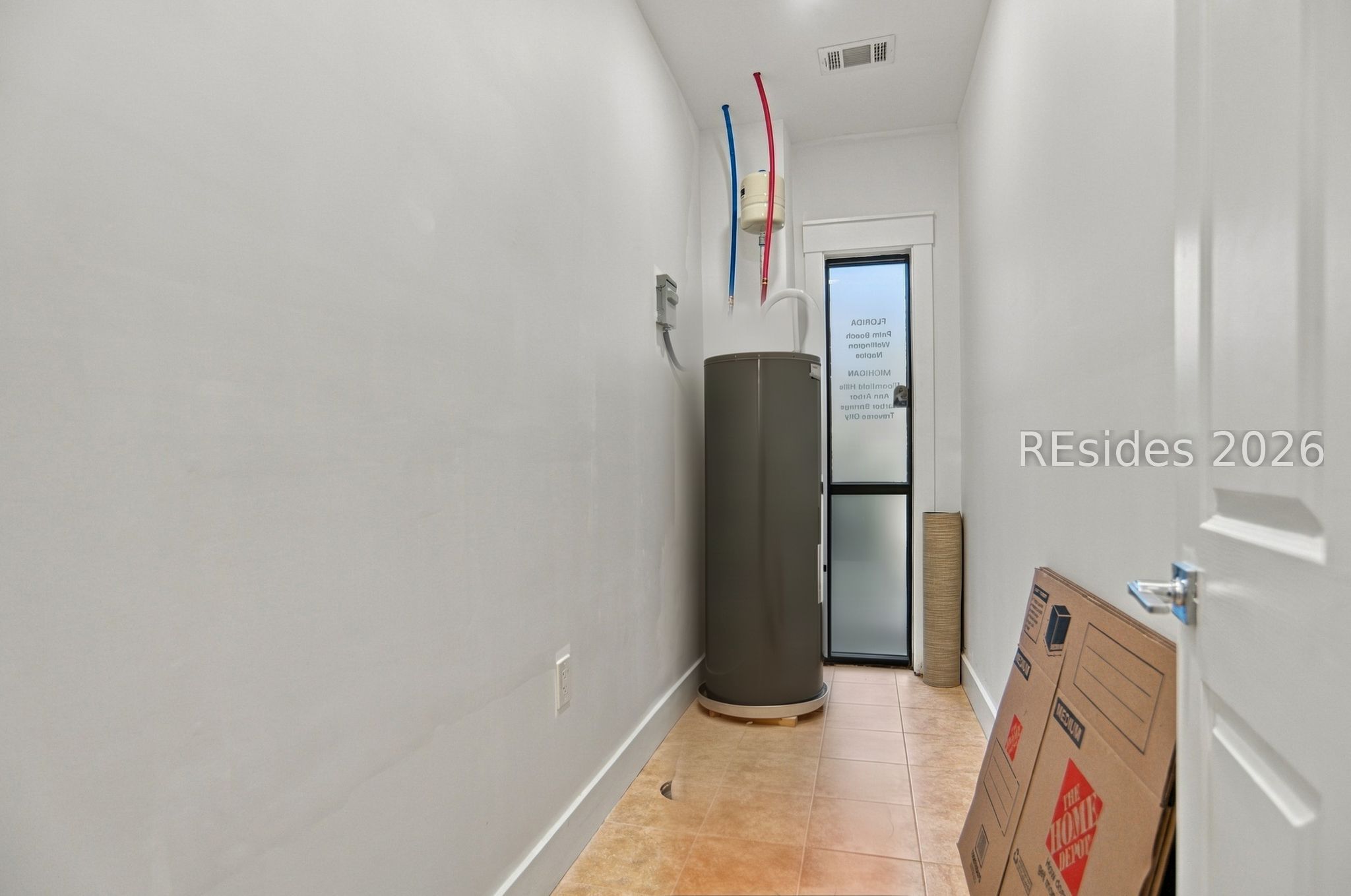 Utility room with a tall water heater, exposed pipes, and cardboard boxes.