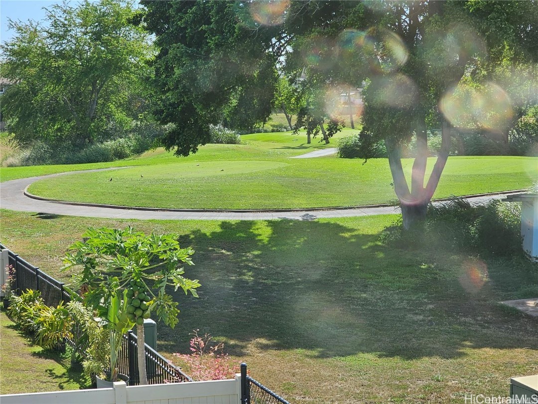 Park view with a curving path, mature trees, and a fenced lawn.