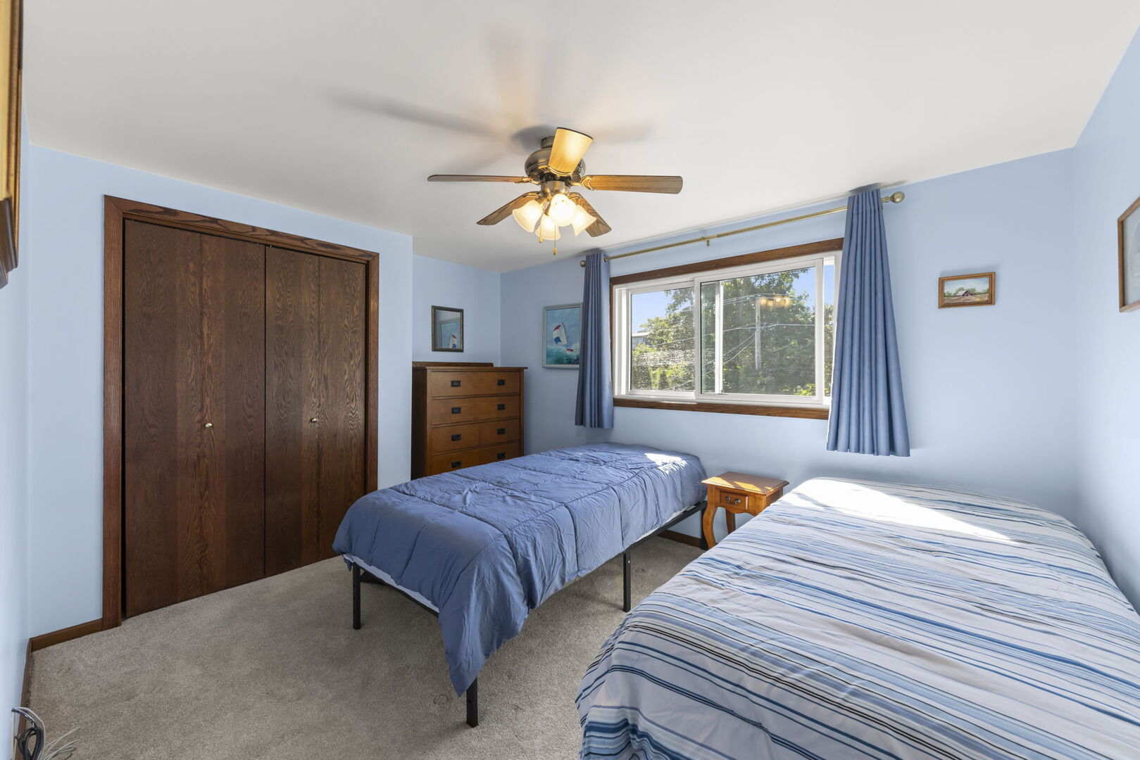 Bedroom with two single beds, blue bedding, and a large dark wood closet.