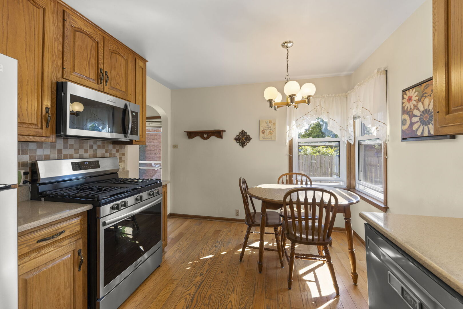 Kitchen and dining area with oak cabinets, stainless steel appliances, and a table by bay windows.