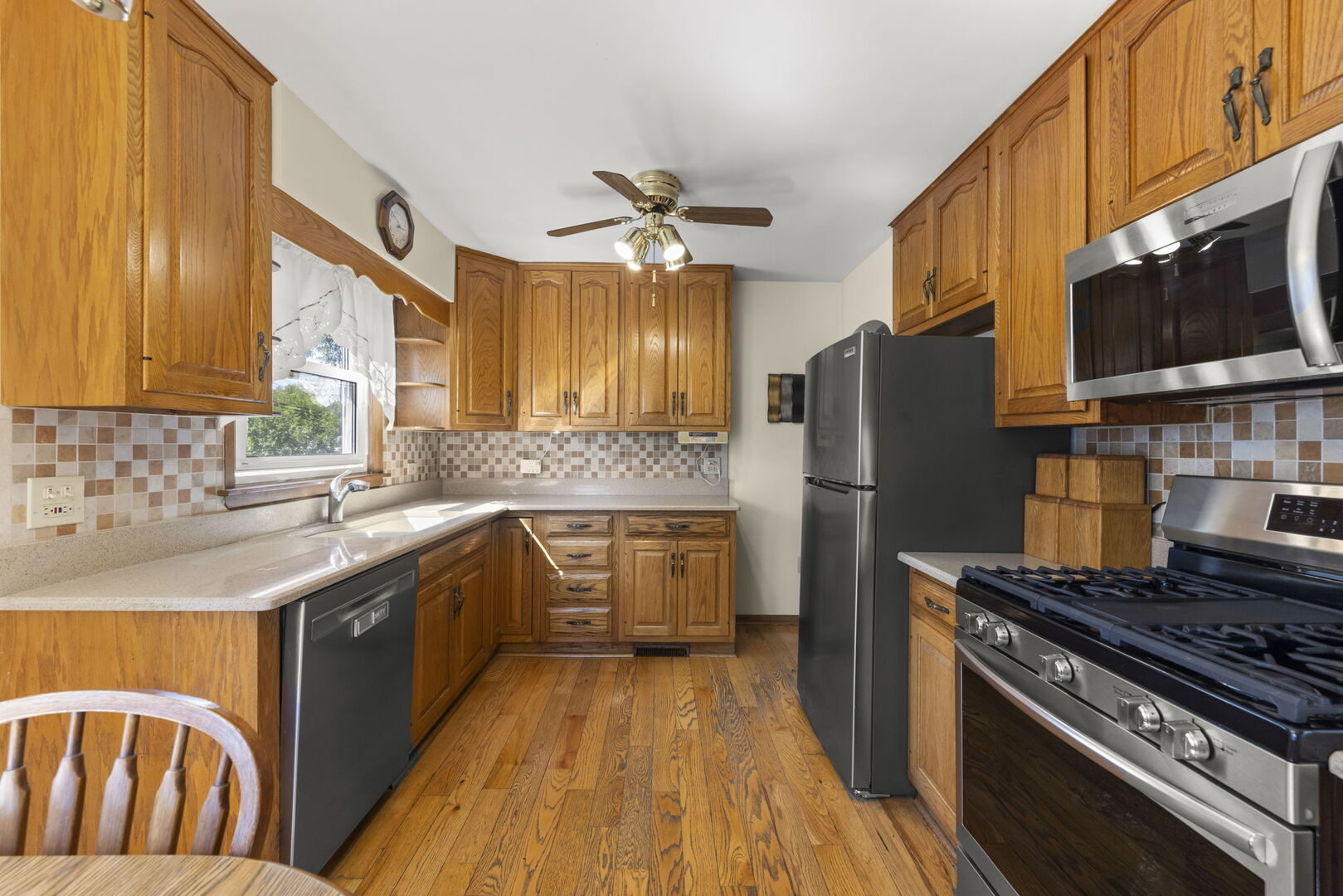 Kitchen with honey-toned wood cabinets, hardwood floors, and stainless steel appliances.