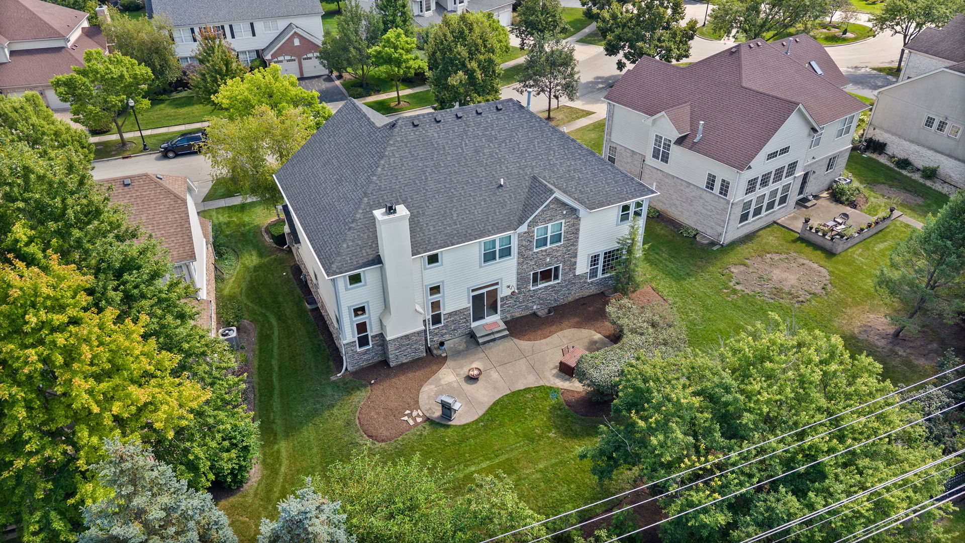 Aerial view of a two-story home and its landscaped backyard with a curved patio.
