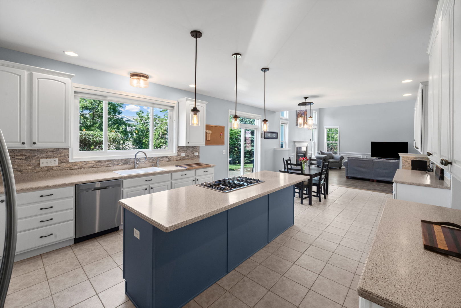 Kitchen with a blue island, white cabinetry, and an open dining and living area.