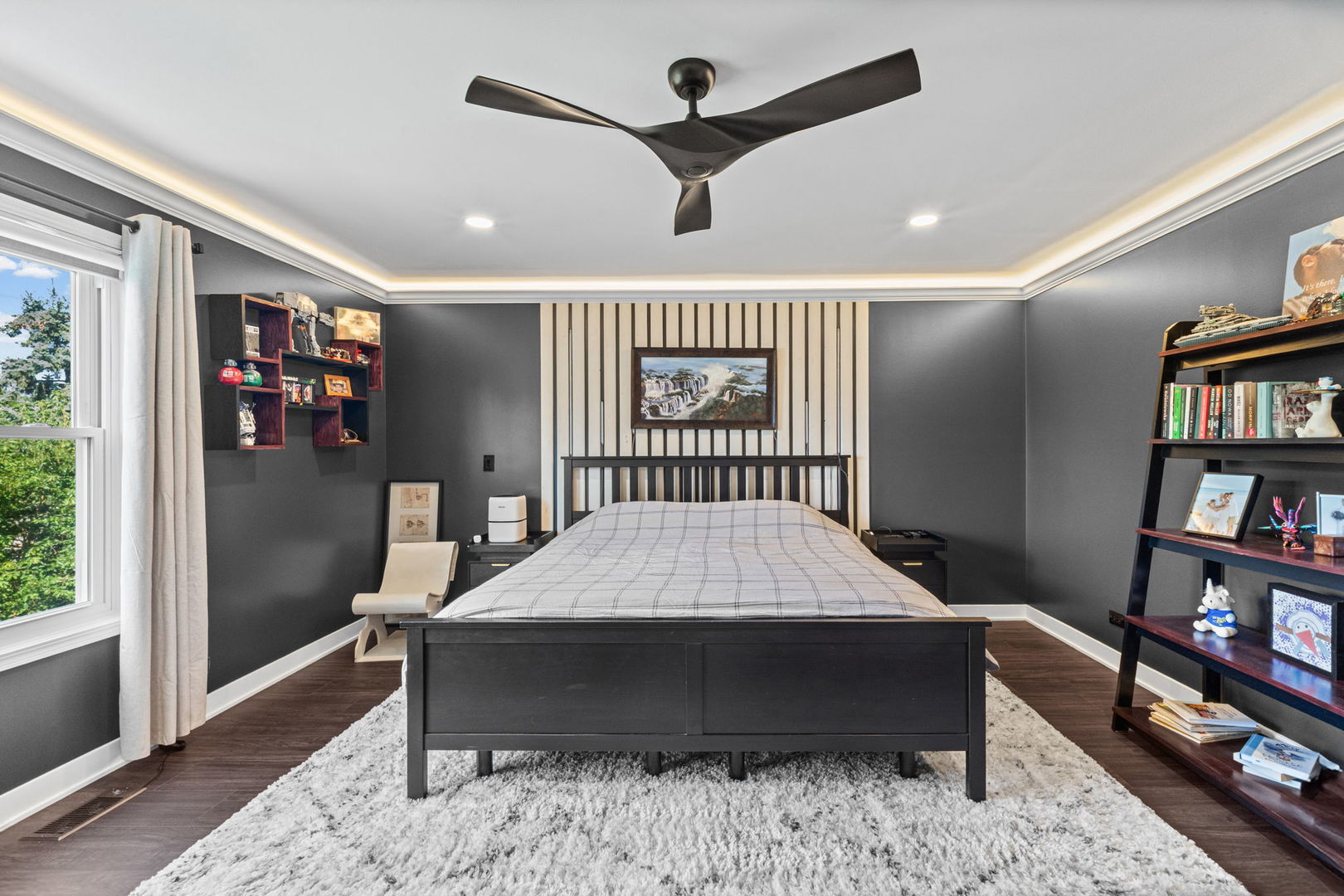 Bedroom with a black bed, striped accent wall, large window, and dark gray walls.