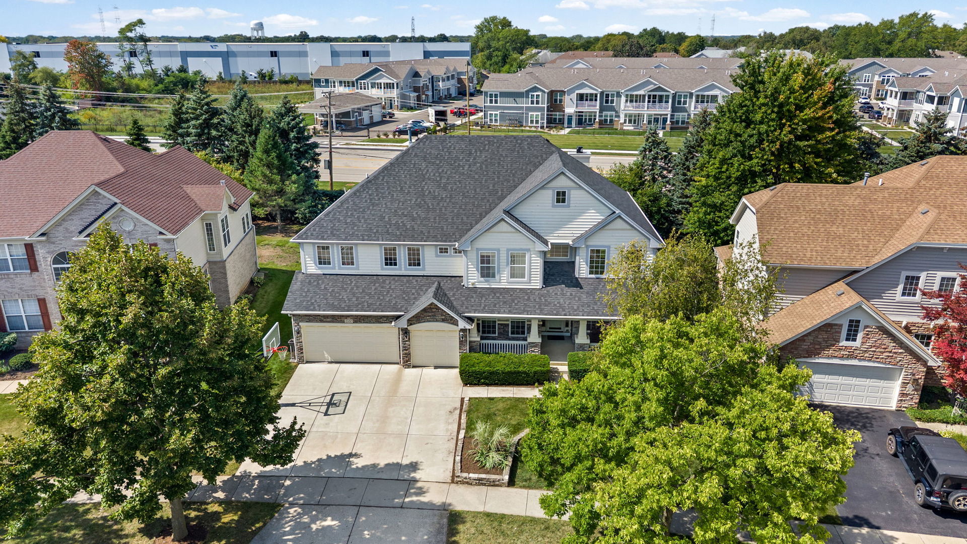 Aerial view of a two-story home with a wide driveway, three-car garage, and basketball hoop.