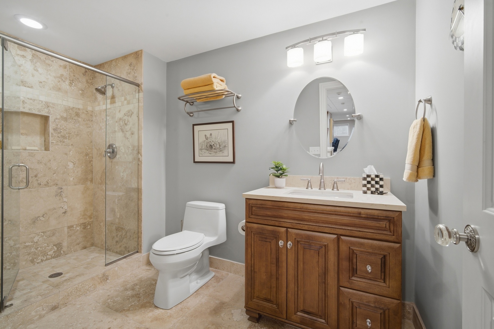 Bathroom with a beige stone-tile shower and dark wood vanity.