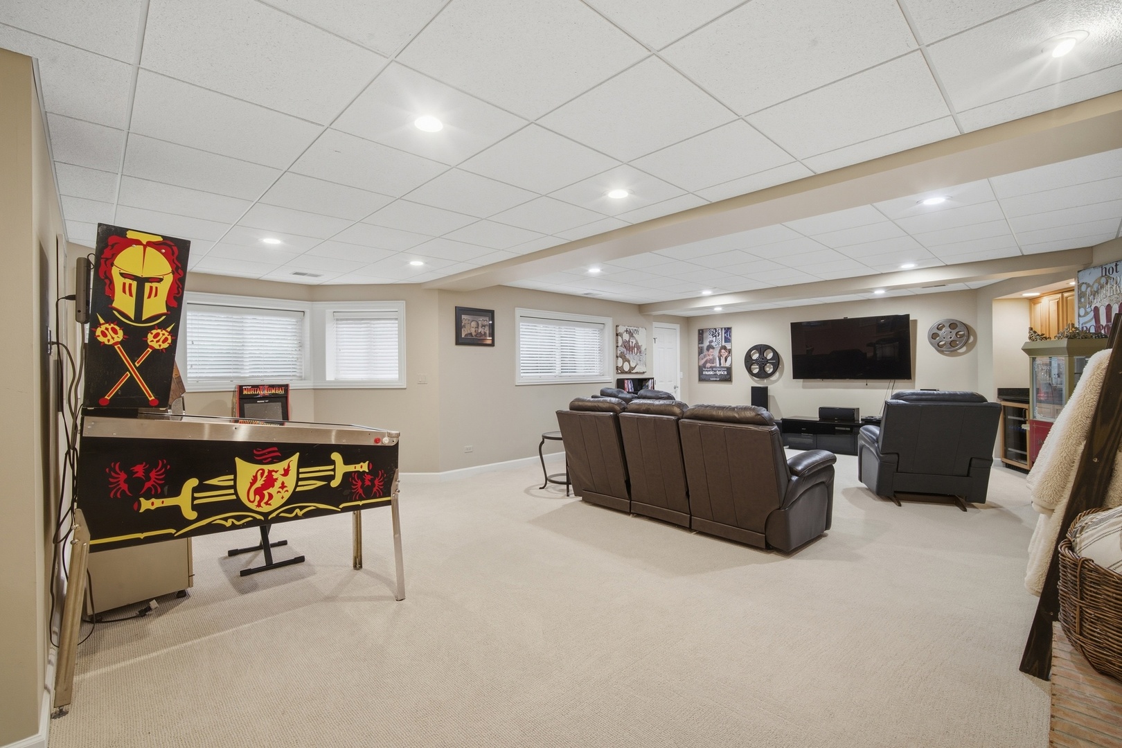 Basement entertainment room with a Mortal Kombat pinball machine and leather theater seating.