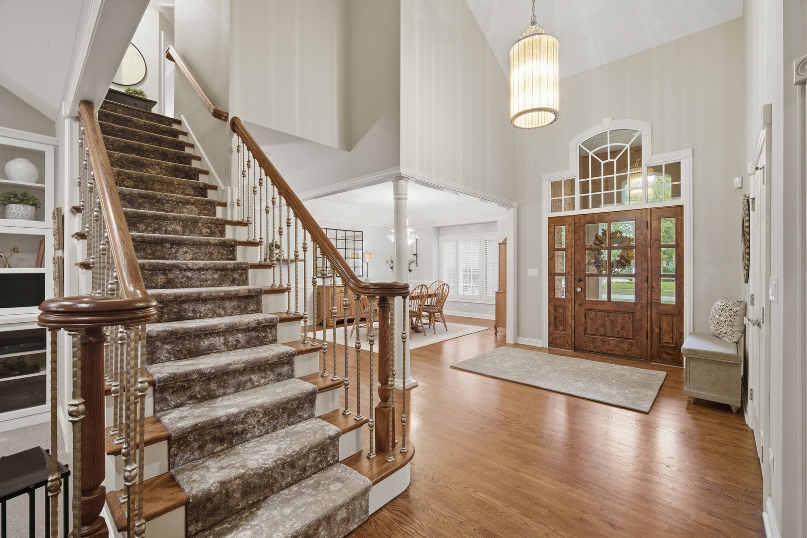 Two-story foyer with a carpeted staircase, hardwood floors, and a wood-and-glass front door.