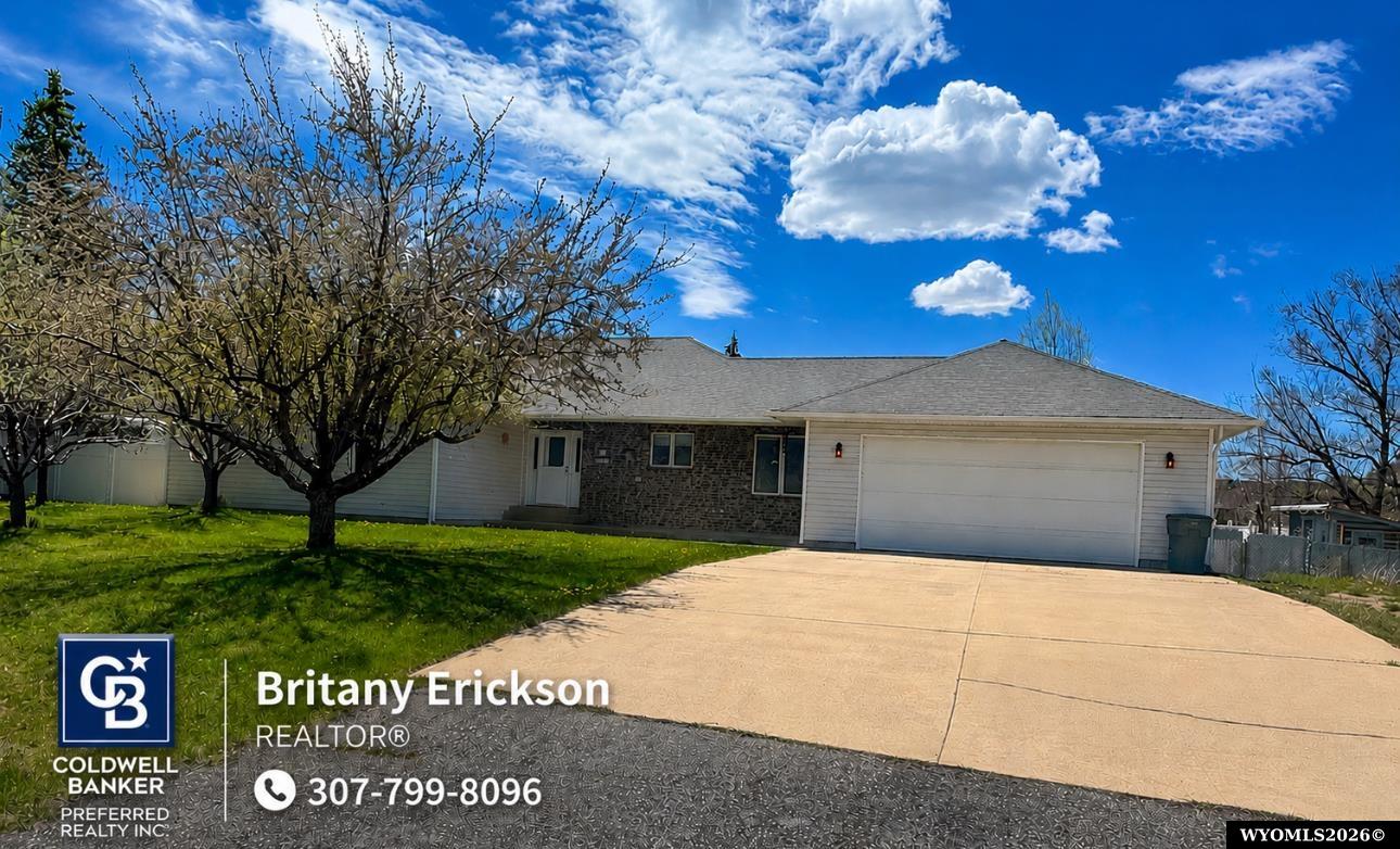 Single-story home with a stone-faced entry, attached garage, and broad concrete driveway.