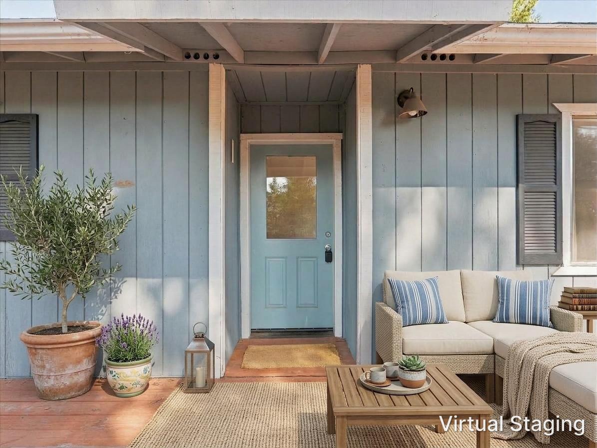 Front porch with a blue door, potted plants, and virtually staged outdoor seating.