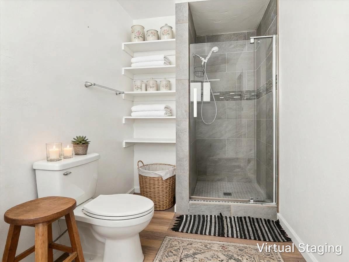 Bathroom with a glass-enclosed gray-tile shower and open shelves displaying folded towels.