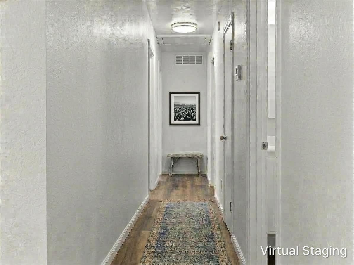 Long hallway with wood floors, a patterned runner, and a bench beneath framed artwork.