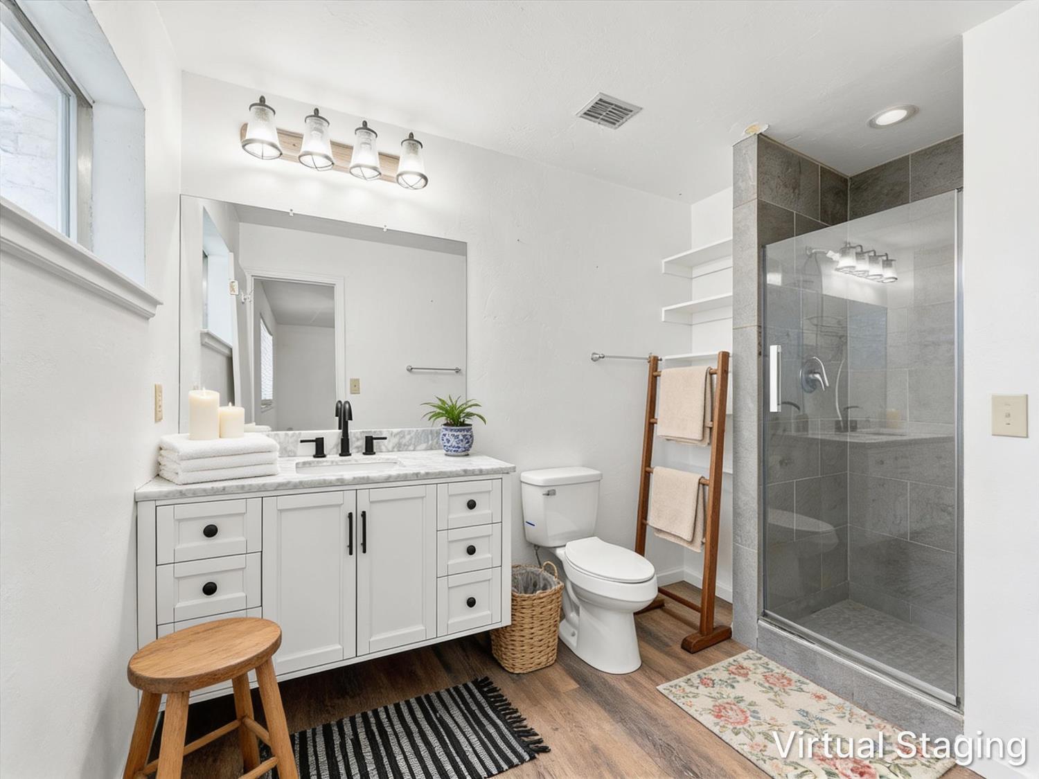 Bathroom with a white vanity and glass-enclosed gray tile shower.