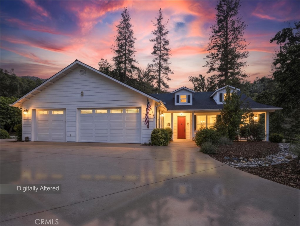 House at dusk with a two-car garage, red front door, and covered porch beneath a pink sunset sky.